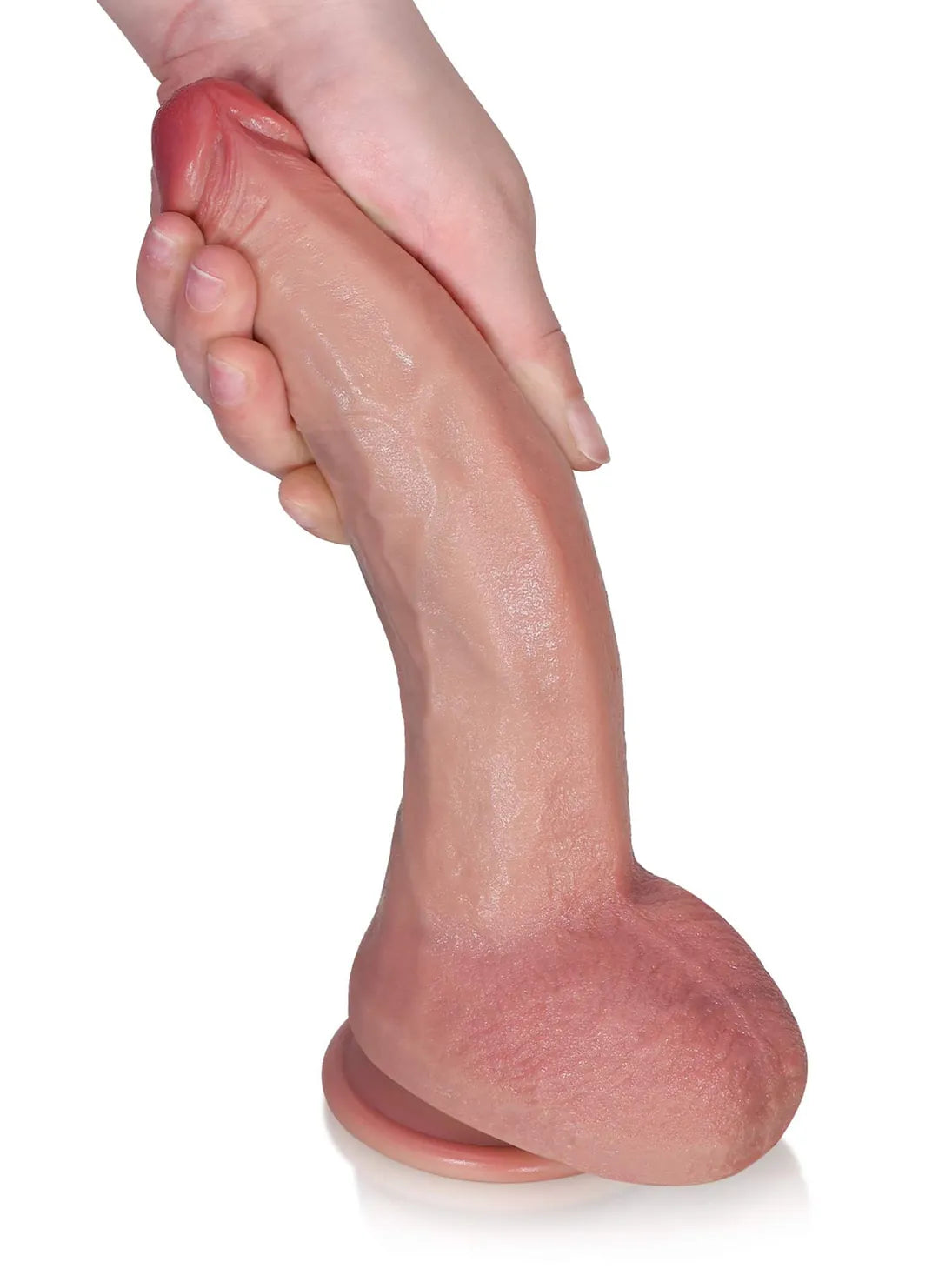Hand bending flesh-colored Tristan dildo, showing curved veined shaft, testicles and suction cup base